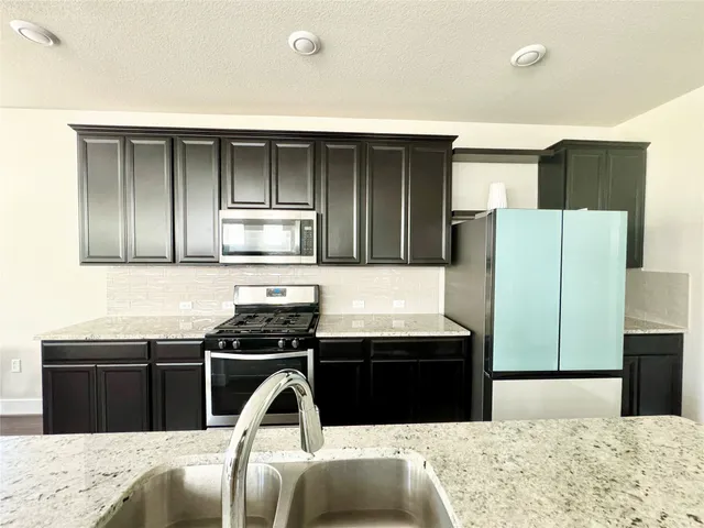 a kitchen with stainless steel appliances kitchen island sink refrigerator and stove