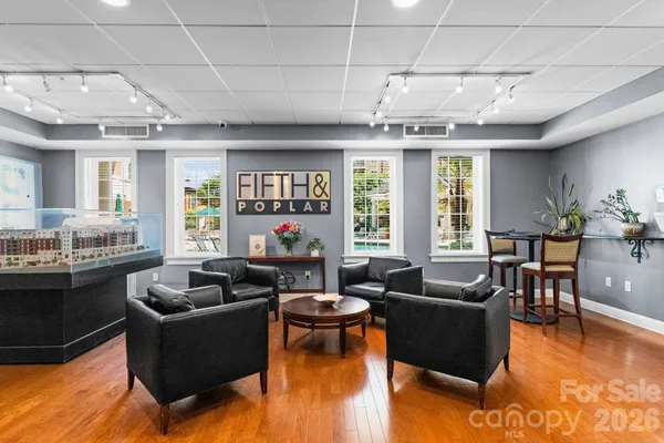 a living room with couches and kitchen view with wooden floor