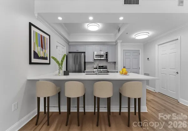 a kitchen with stainless steel appliances a dining table chairs and wooden floor