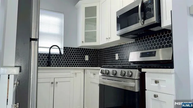a kitchen with granite countertop white cabinets and stainless steel appliances