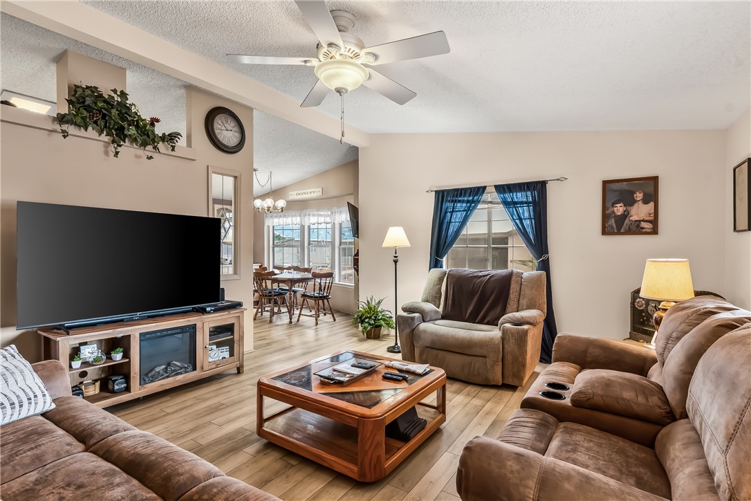 1545 East El Rodeo Road, Unit 58 Fort Mohave, AZ 86426 - Photo 11 of 47 Living room with ceiling fan, wood finished floors, lofted ceiling, and a textured ceiling