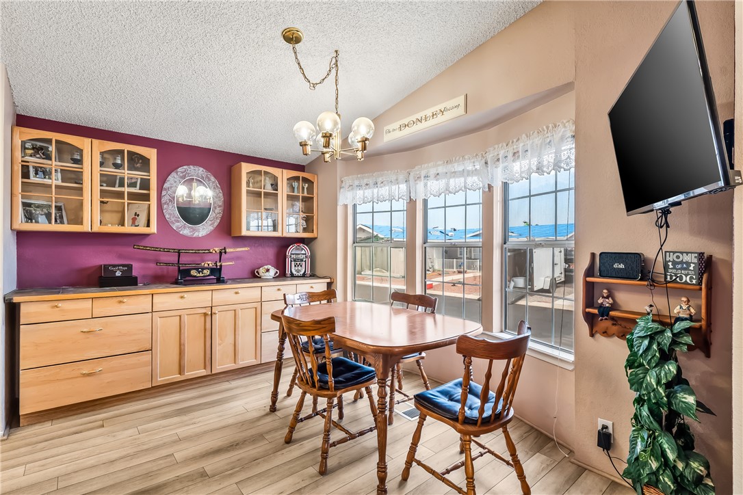 1545 East El Rodeo Road, Unit 58 Fort Mohave, AZ 86426 - Photo 12 of 47 Dining space with light wood finished floors, vaulted ceiling, a chandelier, and a textured ceiling