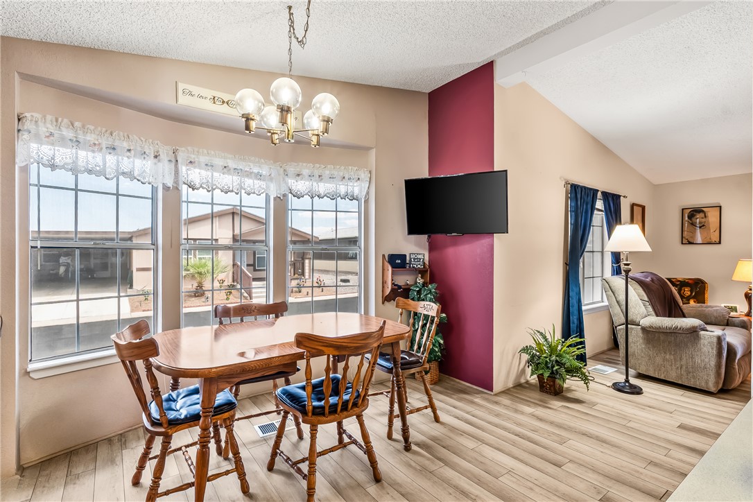1545 East El Rodeo Road, Unit 58 Fort Mohave, AZ 86426 - Photo 13 of 47 Dining space with a chandelier, wood finished floors, plenty of natural light, and a textured ceiling