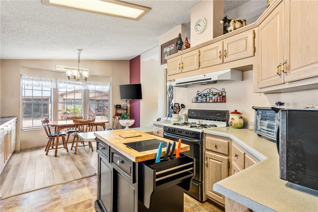 1545 East El Rodeo Road, Unit 58 Fort Mohave, AZ 86426 - Photo 17 of 47 Kitchen featuring butcher block counters, light brown cabinetry, black appliances, pendant lighting, and a textured ceiling