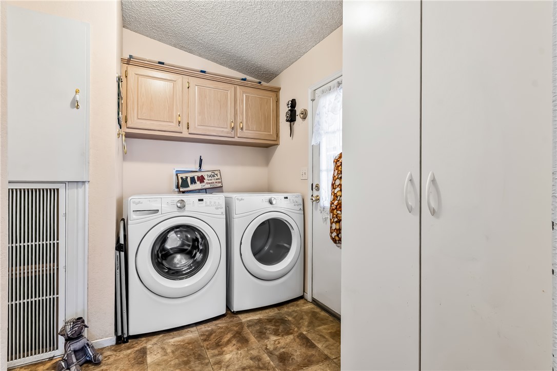 1545 East El Rodeo Road, Unit 58 Fort Mohave, AZ 86426 - Photo 18 of 47 Laundry area with a textured ceiling, cabinet space, independent washer and dryer, and stone finish floors