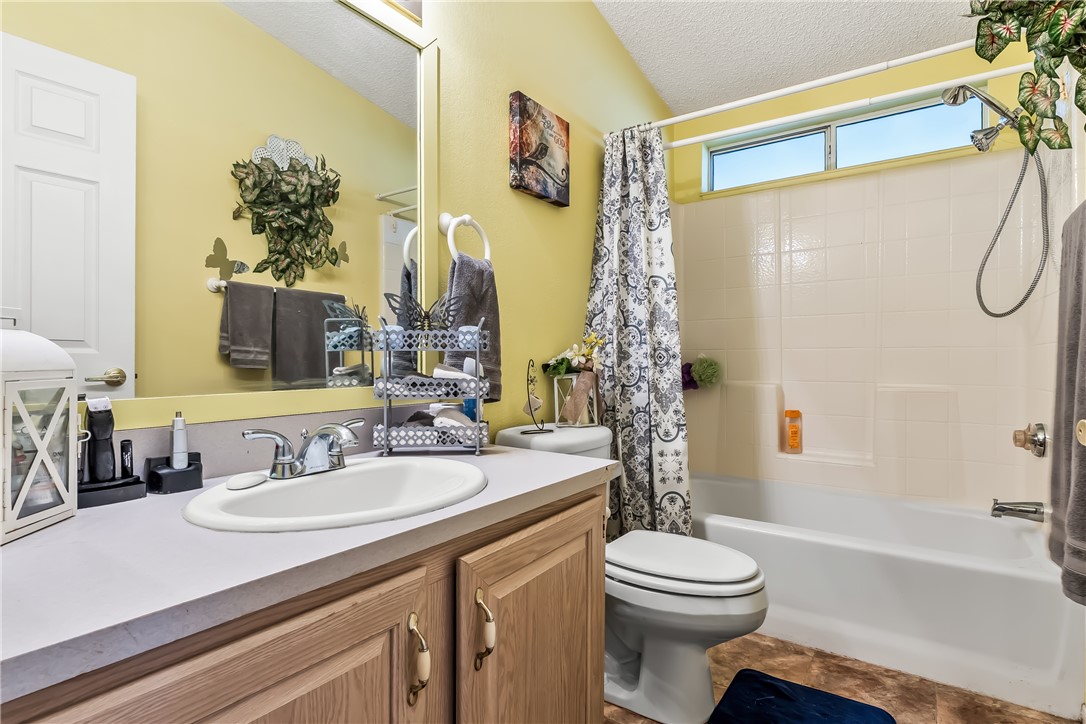 1545 East El Rodeo Road, Unit 58 Fort Mohave, AZ 86426 - Photo 28 of 47 Bathroom featuring shower / bath combo with shower curtain, a textured ceiling, vanity, and tile patterned flooring