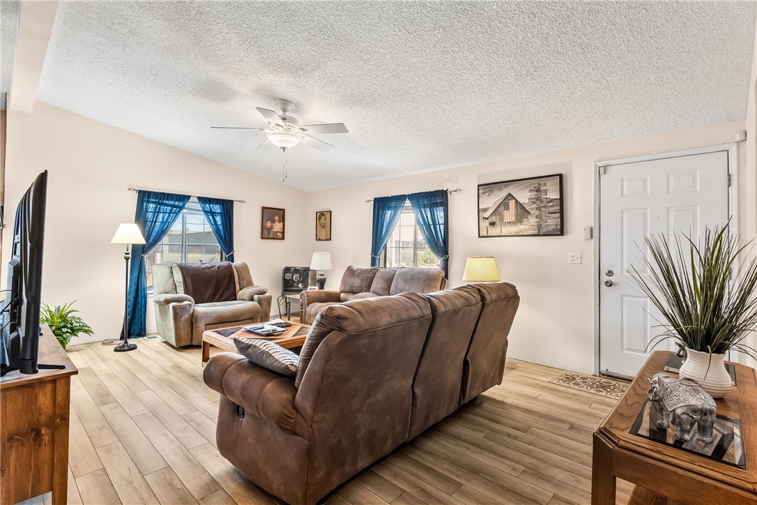 1545 East El Rodeo Road, Unit 58 Fort Mohave, AZ 86426 - Photo 7 of 47 Living area with a textured ceiling, ceiling fan, light wood-type flooring, and lofted ceiling