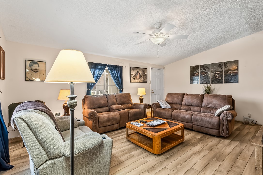 1545 East El Rodeo Road, Unit 58 Fort Mohave, AZ 86426 - Photo 8 of 47 Living room with a textured ceiling, lofted ceiling, wood finished floors, and ceiling fan