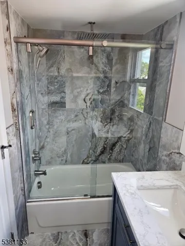 a bathroom with a granite countertop bathtub shower sink and vanity