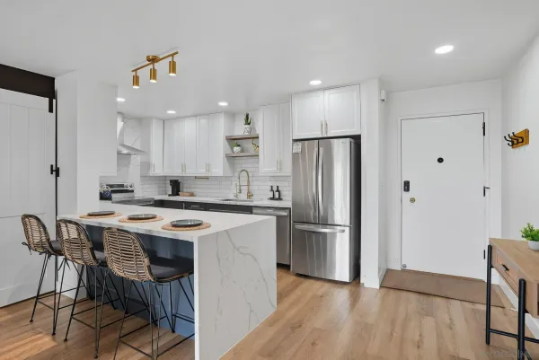 a kitchen with stainless steel appliances a dining table chairs refrigerator and sink