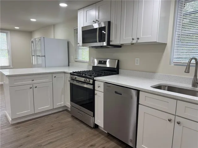 a kitchen with granite countertop white cabinets and stainless steel appliances