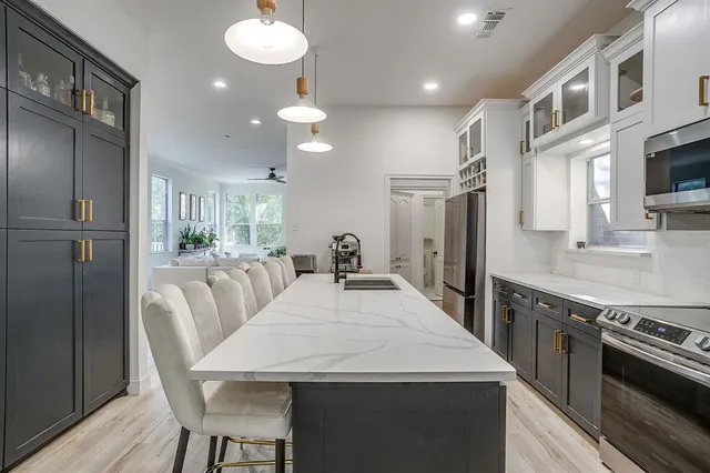 a large kitchen with stainless steel appliances kitchen island granite countertop a table chairs in it and wooden floors