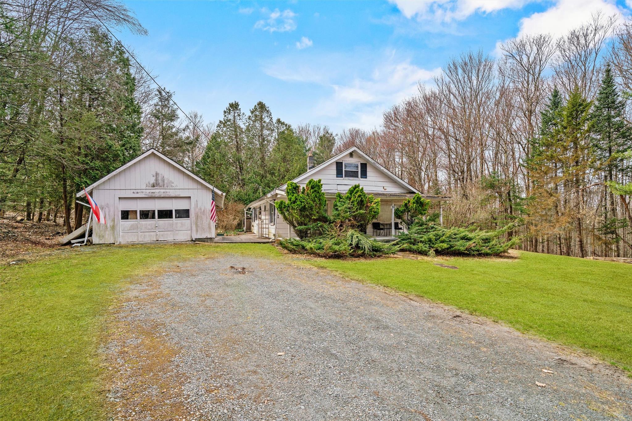 53 Dill Road Forestburgh, NY 12777 - Photo 1 of 1 View of front of home with covered porch, an outbuilding, a front lawn, gravel driveway, and a garage
