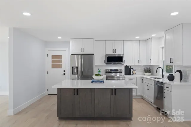 a kitchen with stainless steel appliances a sink a stove a refrigerator cabinets and a refrigerator