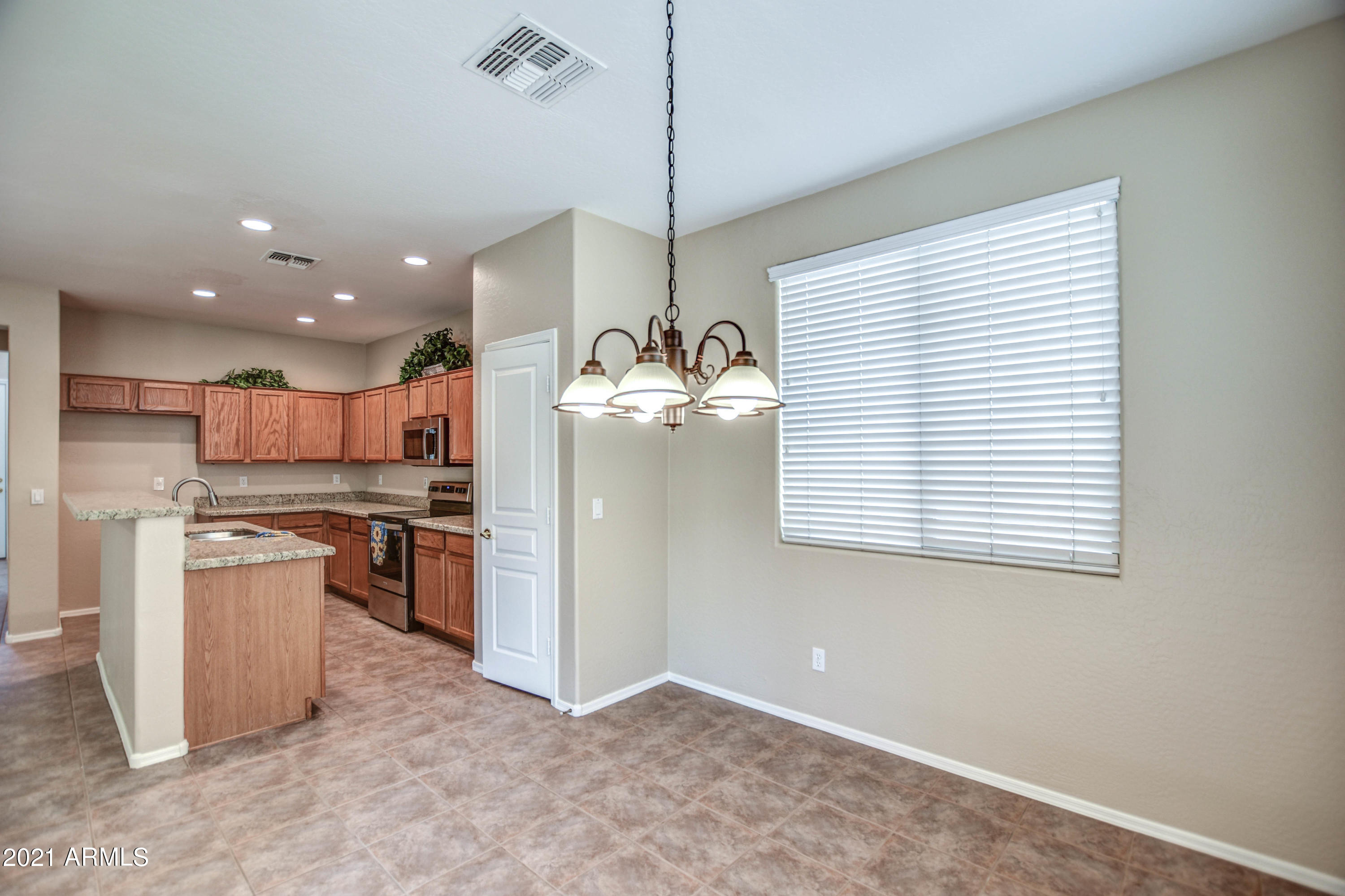 3787 East Chickadee Road Gilbert, AZ 85297 - Photo 5 of 41 a kitchen with stainless steel appliances granite countertop a refrigerator a sink dishwasher a stove and a dining table with wooden floor