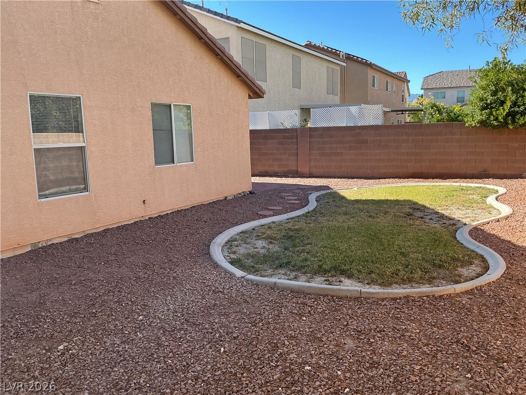 8108 Roundup Ridge Street Las Vegas, NV 89131 - Photo 21 of 21 A low-maintenance yard features decorative gravel and a small, well-defined patch of green lawn.