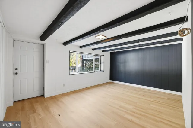 a view of an empty room with window and wooden floor
