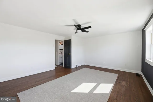 an empty room with wooden floor and ceiling fan
