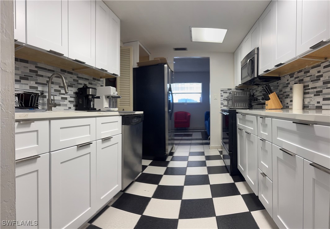 806 West 80th Place Hialeah, FL 33014 - Photo 15 of 17 a kitchen with a checkered floor and white cabinets