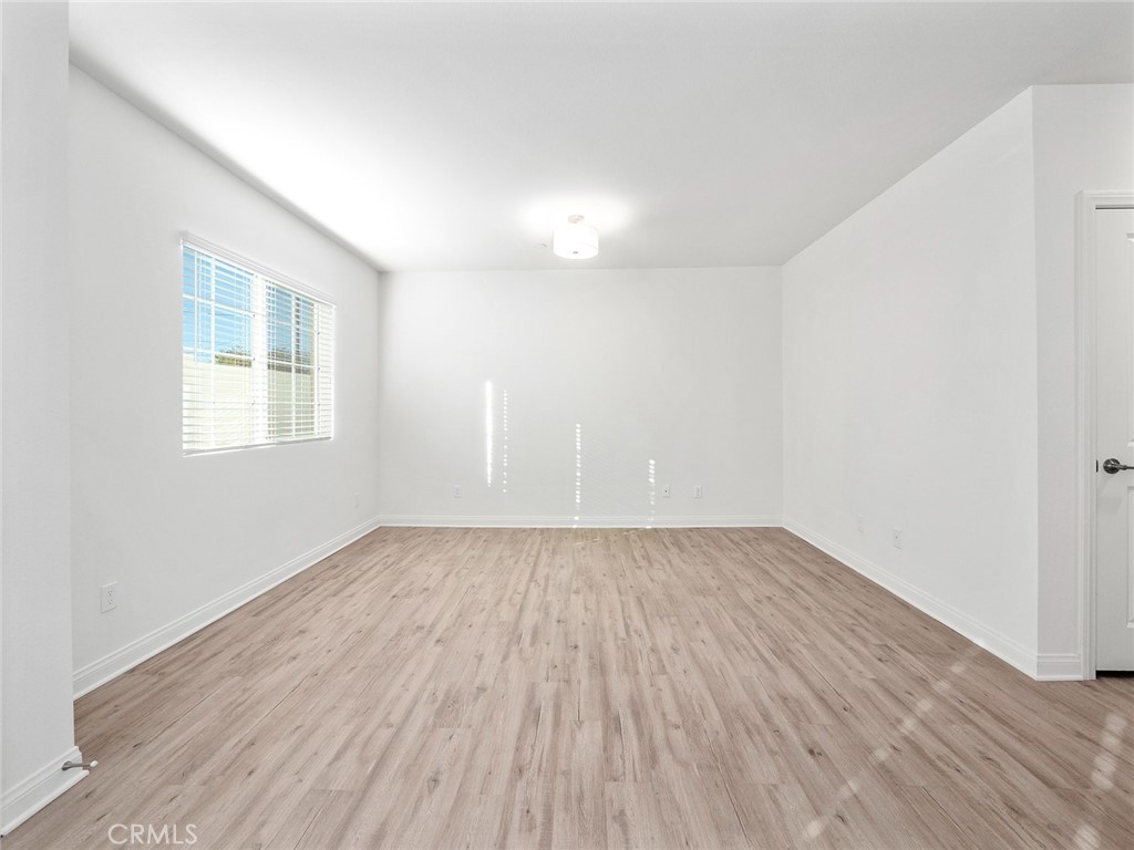 1325 West Grand Avenue, Unit 3 Pomona, CA 91766 - Photo 8 of 30 an empty room with wooden floor and windows