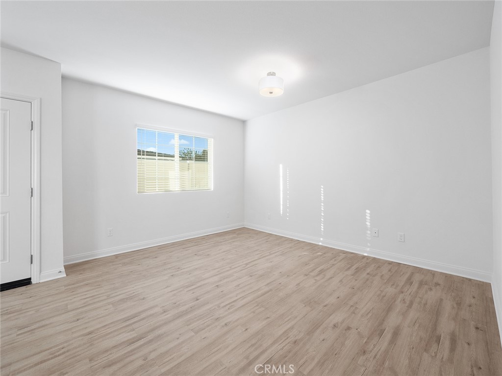 1325 West Grand Avenue, Unit 3 Pomona, CA 91766 - Photo 9 of 30 a view of an empty room with wooden floor and a window