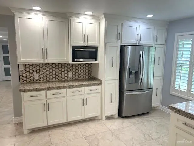 a kitchen with white cabinets and refrigerator