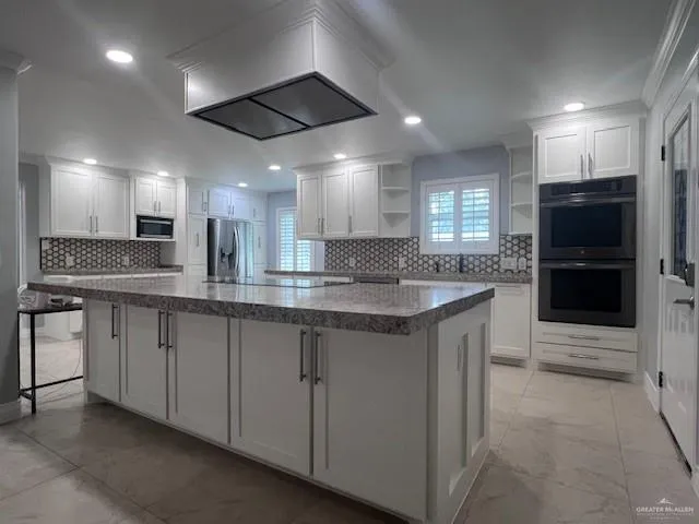 a large kitchen with stainless steel appliances kitchen island granite countertop a large counter top and a stove top oven