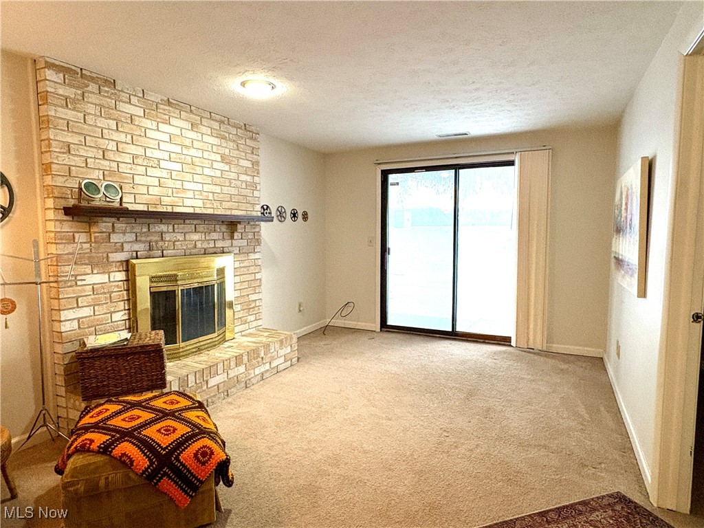 4015 Marks Road, Unit 3C Medina, OH 44256 - Photo 20 of 36 Living room with carpet, a textured ceiling, and a brick fireplace