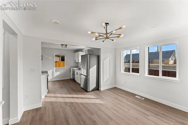 a view of a big room with wooden floor and a kitchen