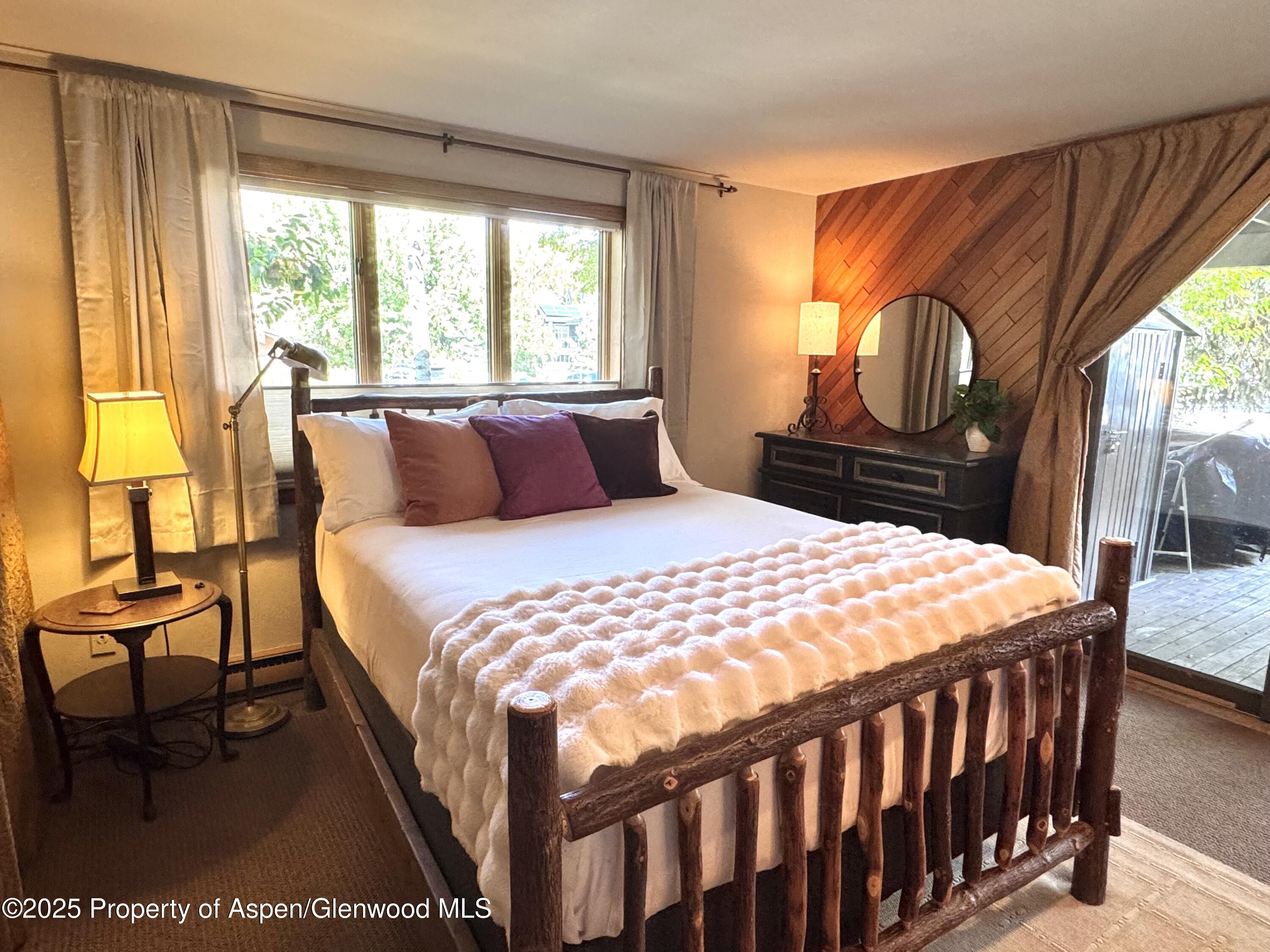 125 East Hyman Avenue, Unit 1A Aspen, CO 81611 - Photo 6 of 19 a bedroom with a bed a dresser next to a window