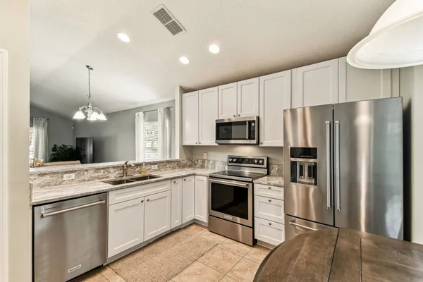 a kitchen with granite countertop a sink stainless steel appliances and white cabinets