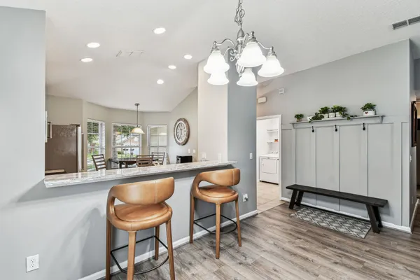a living room with furniture kitchen view and a chandelier