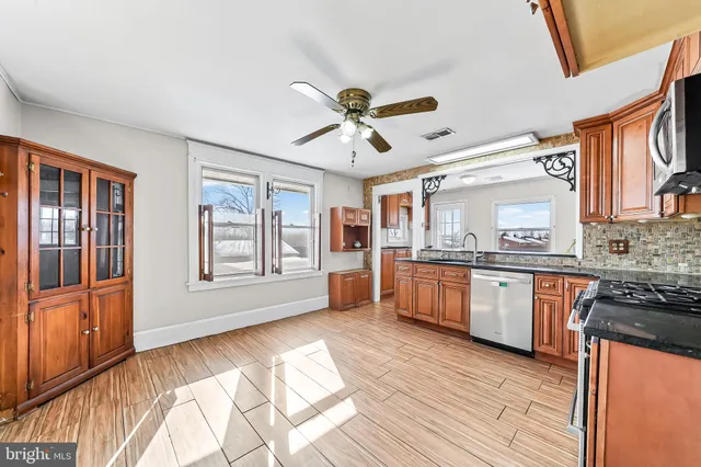 a large kitchen with stainless steel appliances granite countertop a stove a sink dishwasher and a black refrigerator