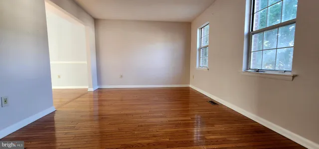 a view of an empty room with wooden floor and windows
