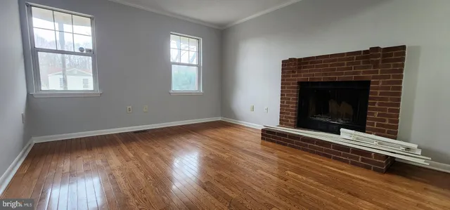 an empty room with wooden floor a fireplace and windows