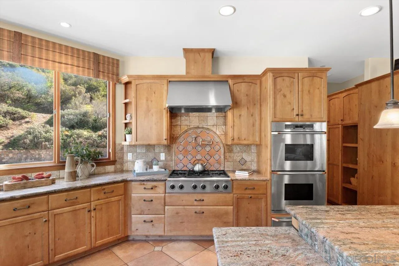 11760 Betsworth Road Valley Center, CA 92082 - Photo 13 of 47 a kitchen with stainless steel appliances kitchen island granite countertop a stove and a refrigerator