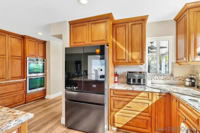 a kitchen with stainless steel appliances granite countertop a refrigerator a stove and a sink with cabinets