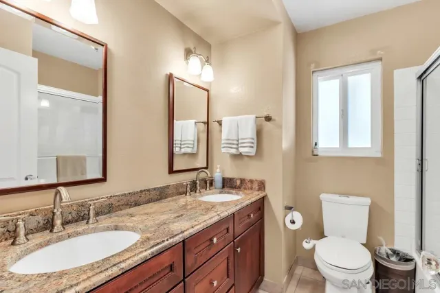a bathroom with a granite countertop toilet a sink and a mirror