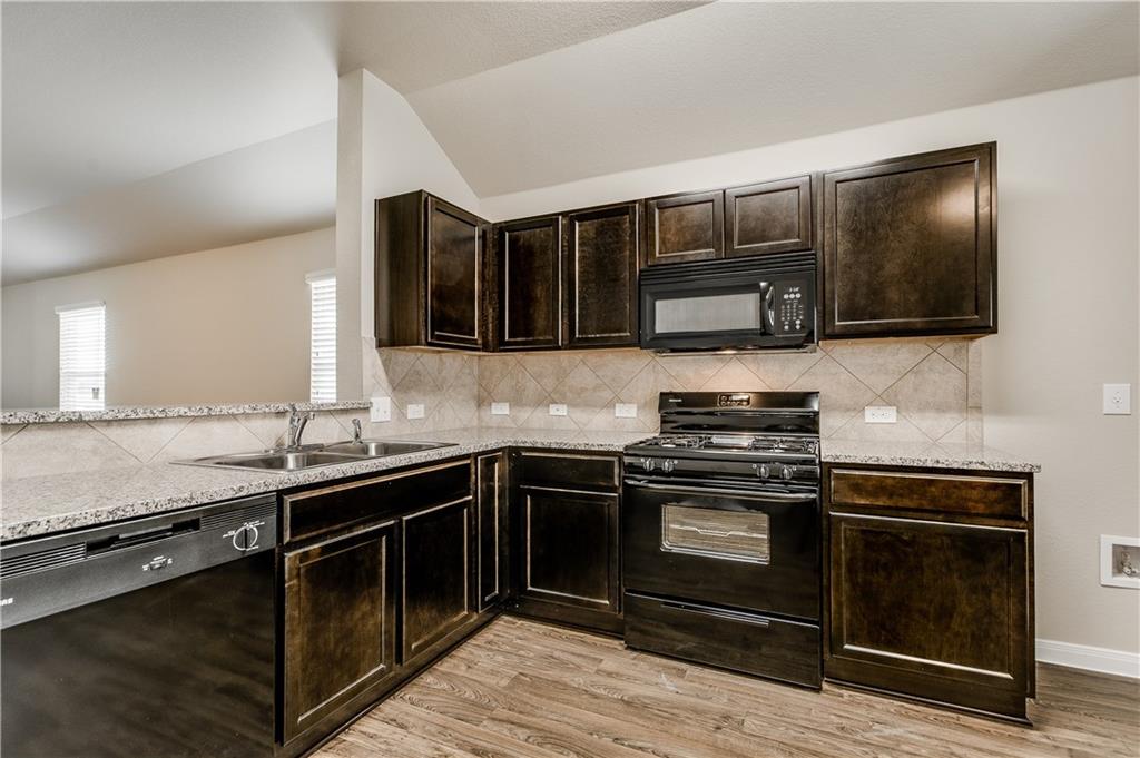 185 Voss Kyle, TX 78640 - Photo 3 of 26 a kitchen with stainless steel appliances wooden cabinets stove and microwave
