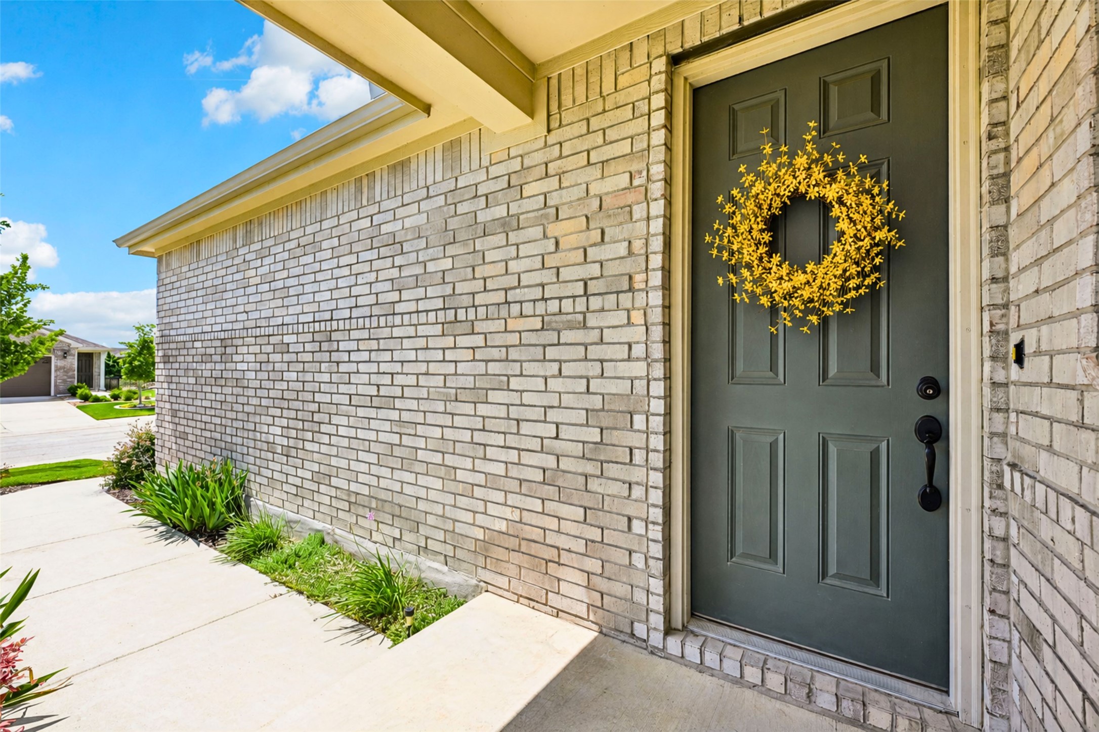 401 Yorktown Street Georgetown, TX 78633 - Photo 2 of 38 Front entrance featuring a paneled door with matte black hardware, light-colored brick exterior, covered porch, concrete walkway, and landscaping