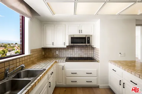 a kitchen with stainless steel appliances a stove a sink and white cabinets