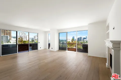 a view of an empty room with a fireplace and window