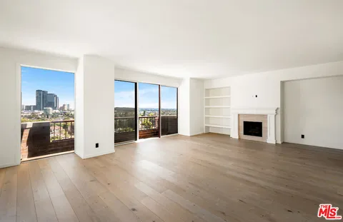 an empty room with windows and fireplace
