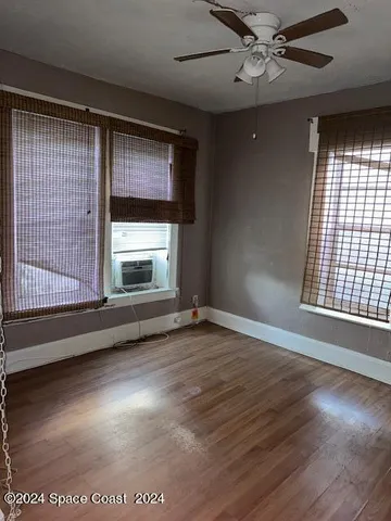 a view of an empty room with wooden floor and a window