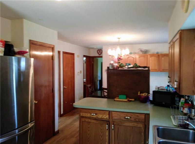 105 Elliott Road Grove City, PA 16127 - Photo 11 of 20 The eat-in Kitchen, with wide-plank oak flooring, hosts a breakfast/bakery bar, Commercial Whirlpool gas stove (currently using propane), oak cabinetry, and a convenient 6 x 5 laundry area just inside the new side door entrance