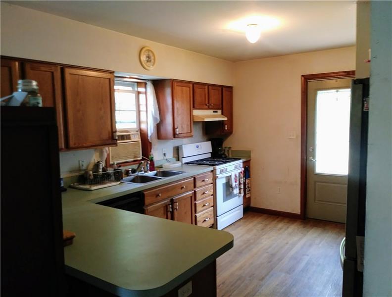 105 Elliott Road Grove City, PA 16127 - Photo 9 of 20 The eat-in Kitchen, with wide-plank oak flooring, hosts a breakfast/bakery bar, Commercial Whirlpool gas stove (currently using propane), oak cabinetry, and a convenient 6 x 5 laundry area just inside the new side door entrance
