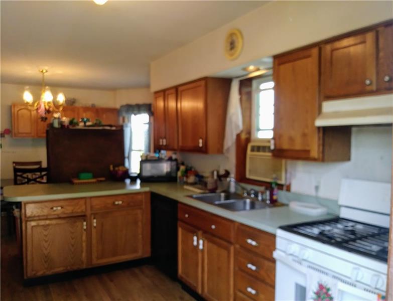 105 Elliott Road Grove City, PA 16127 - Photo 10 of 20 The eat-in Kitchen, with wide-plank oak flooring, hosts a breakfast/bakery bar, Commercial Whirlpool gas stove (currently using propane), and oak cabinetry