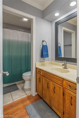 a spacious bathroom with a granite countertop sink toilet a mirror and shower