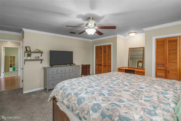 a bedroom with a bed and a flat tv screen on dresser