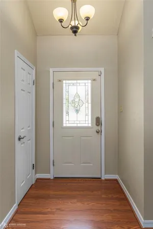 an empty room with wooden floor chandelier fan and windows